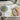 Watercolour drawings of a sardine on brown paper and two lemons around it.  To the left is a blue plate of green olives.