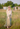 Long Green Linen Skirt with buttons on the front. It is on a model standing in a green field with a blurry background