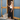 Linen Black Florence Pant placed on a model standing on the front porch of a blue and wood building
