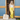 Lemon Lime Linen Pant placed on a model standing on the front porch of a blue and wood building