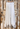 Long White Linen Skirt with buttons on the front, place on a hanger and is hanging against a wooden door