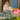 Long Green Linen Skirt with buttons on the front. It is on a model sitting on the front porch of a blue and wood building